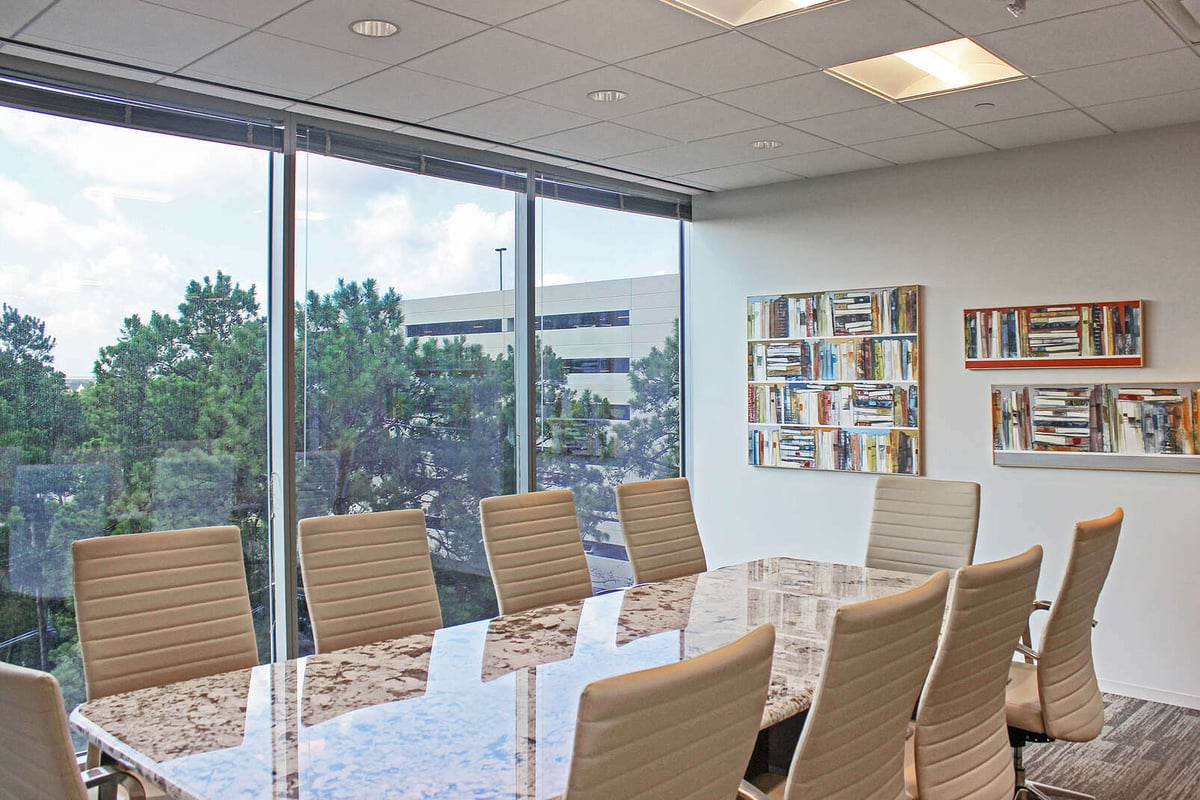 Refined conference table with marble finish, surrounded by white chairs and natural light, remodeled by GSD Construction in Houston, TX