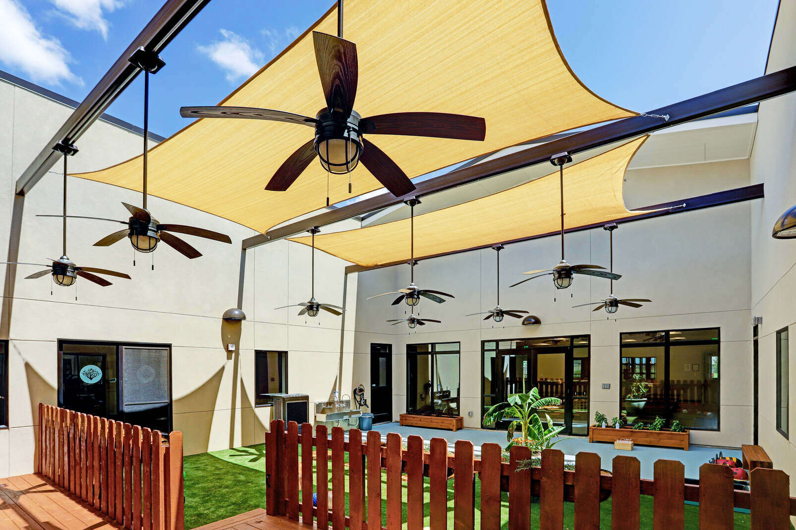 Outdoor courtyard with shade sails, ceiling fans, and landscaping, part of GSD Construction’s Houston, TX renovation